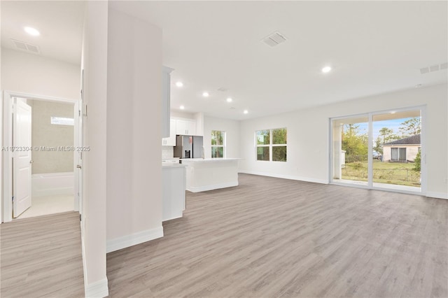 unfurnished living room with a healthy amount of sunlight and light hardwood / wood-style flooring