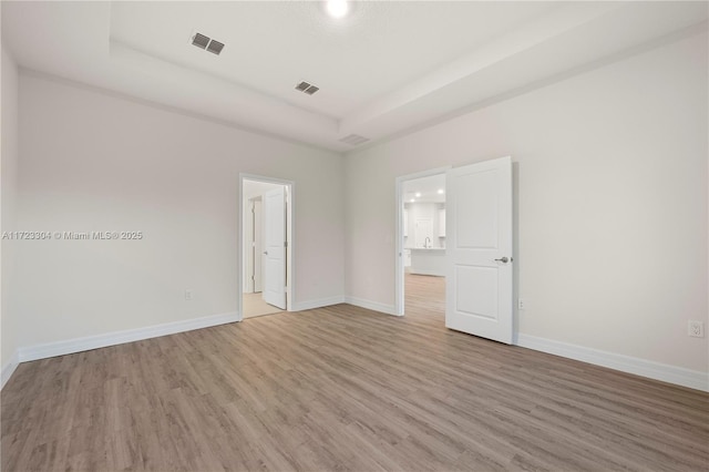 spare room featuring a raised ceiling and hardwood / wood-style floors