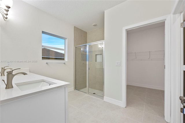 bathroom with tile patterned flooring, vanity, an enclosed shower, and a textured ceiling