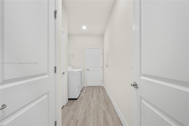 clothes washing area with washer and clothes dryer and light wood-type flooring