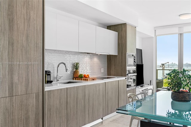 kitchen featuring decorative backsplash, floor to ceiling windows, sink, white cabinetry, and oven