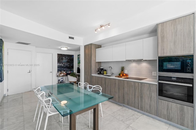 kitchen featuring black appliances, decorative backsplash, white cabinetry, and sink