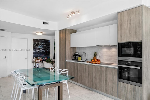 kitchen with backsplash, stainless steel oven, black microwave, sink, and white cabinetry