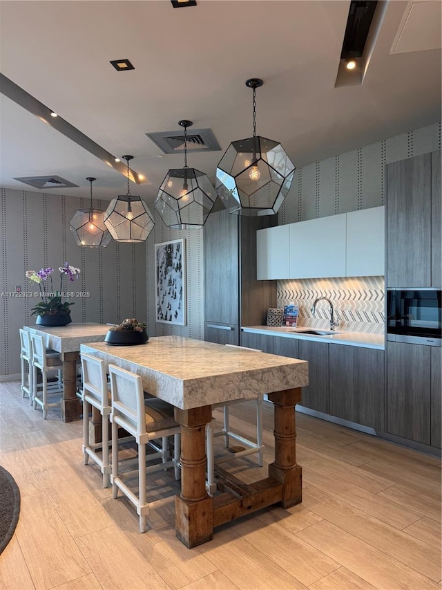 2900 NE 7th Ave Unit 908, Miami, FL 33137 - kitchen with wallpapered walls, light countertops, light wood finished floors, pendant lighting, and modern cabinets