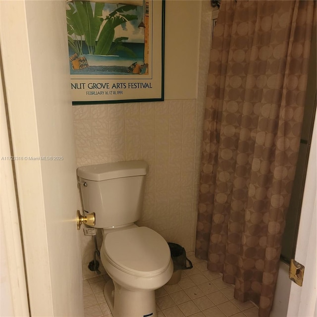 bathroom with tile patterned floors, shower / tub combo with curtain, tile walls, and toilet