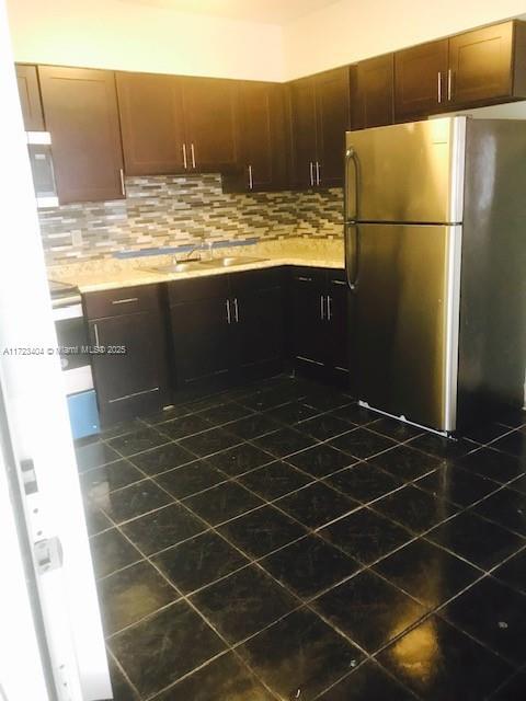 kitchen with decorative backsplash, sink, and stainless steel refrigerator