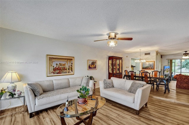 living room with ceiling fan, light hardwood / wood-style flooring, and a textured ceiling