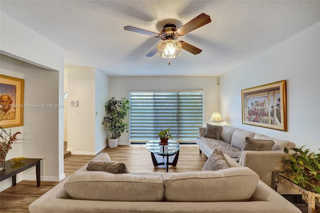 living room with a textured ceiling, light hardwood / wood-style floors, and ceiling fan