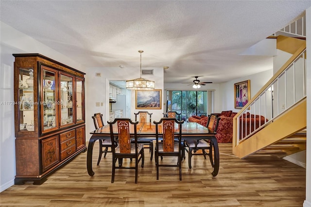 dining area with ceiling fan, hardwood / wood-style floors, and a textured ceiling