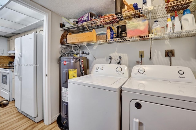 clothes washing area featuring electric water heater, light hardwood / wood-style floors, and washing machine and clothes dryer