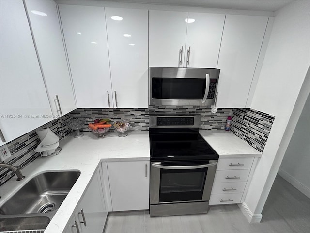 kitchen with white cabinets, stainless steel appliances, tasteful backsplash, and sink