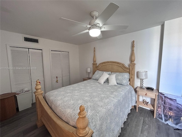 bedroom with ceiling fan, dark wood-type flooring, and multiple closets