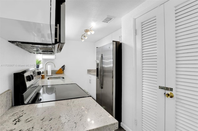 kitchen featuring stove, sink, stainless steel refrigerator with ice dispenser, light stone counters, and white cabinetry