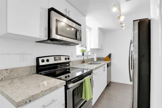 kitchen featuring appliances with stainless steel finishes, sink, white cabinetry, and light stone counters