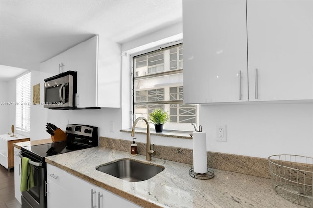 kitchen featuring white cabinetry, sink, light stone counters, and appliances with stainless steel finishes