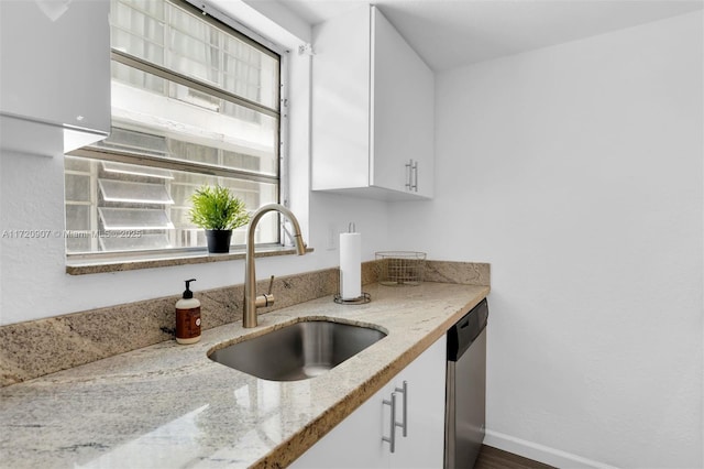 kitchen with white cabinetry, sink, stainless steel dishwasher, and light stone counters