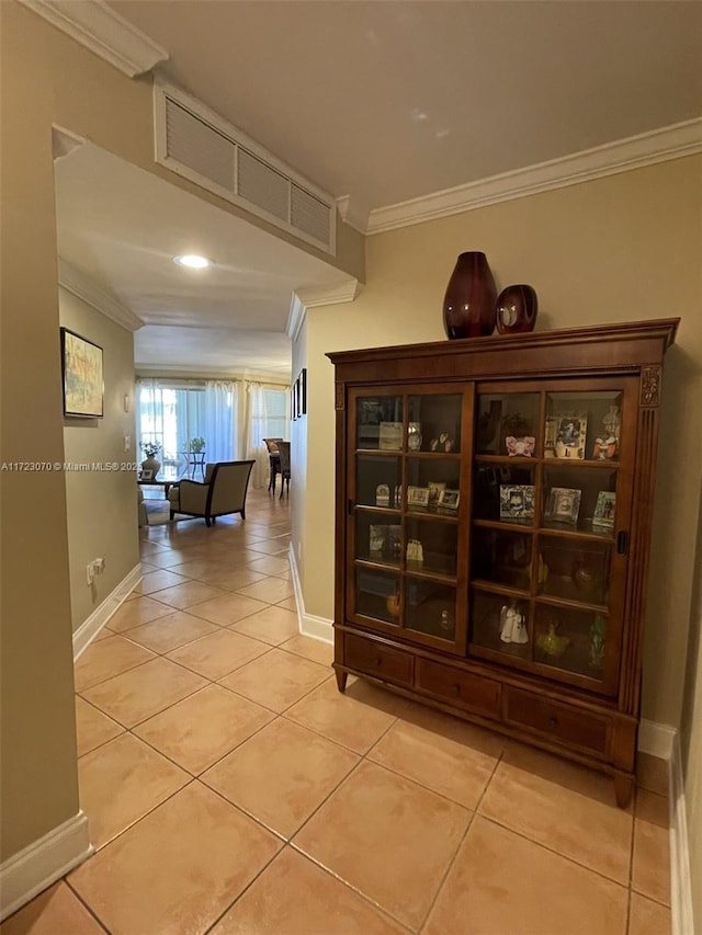 hallway with light tile patterned floors and crown molding