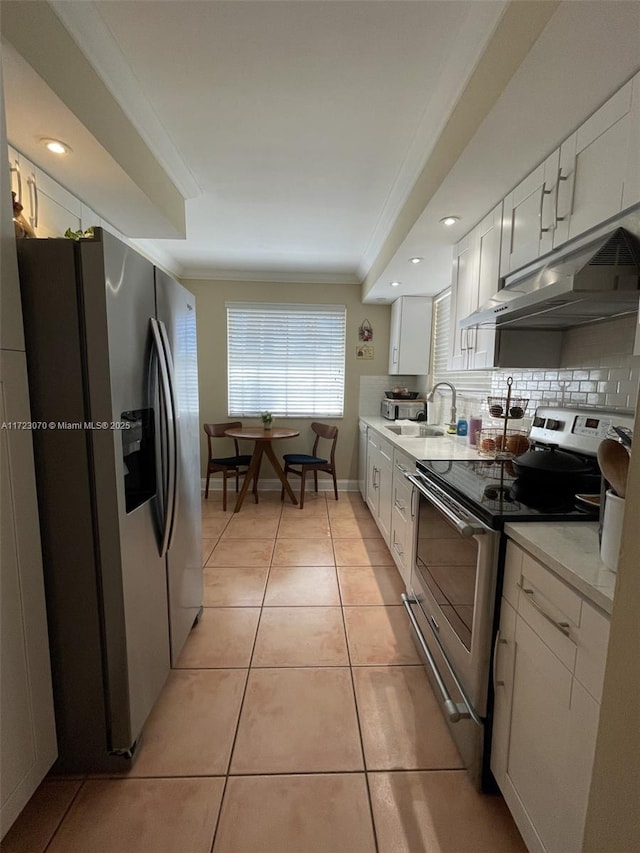 kitchen featuring appliances with stainless steel finishes, crown molding, sink, light tile patterned floors, and white cabinetry