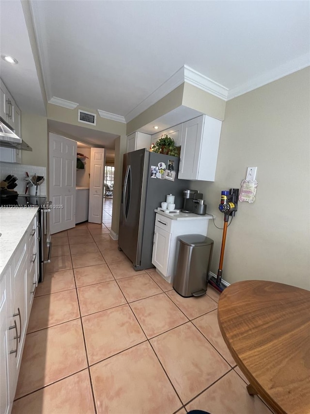 kitchen with white cabinets, appliances with stainless steel finishes, light tile patterned floors, and crown molding