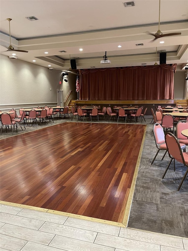 rec room with ceiling fan, wood-type flooring, and a tray ceiling