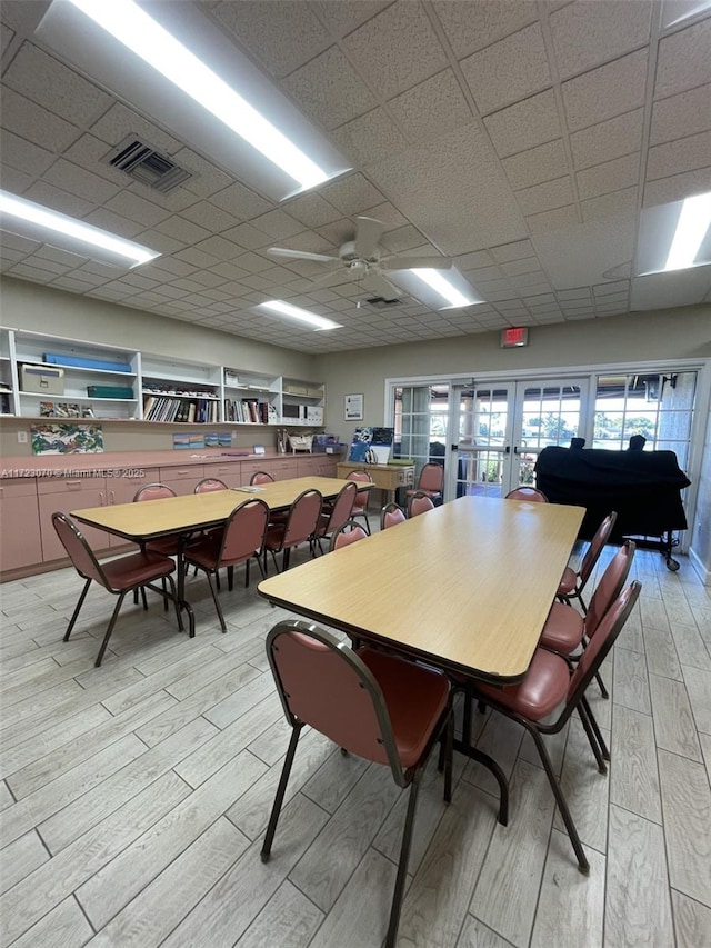 dining room featuring ceiling fan, french doors, and a drop ceiling