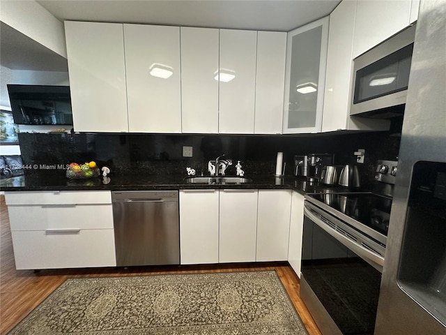 kitchen featuring backsplash, stainless steel appliances, sink, white cabinets, and dark hardwood / wood-style floors