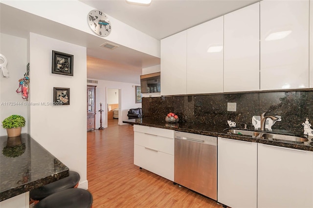 kitchen with sink, white cabinets, dishwasher, and dark stone countertops