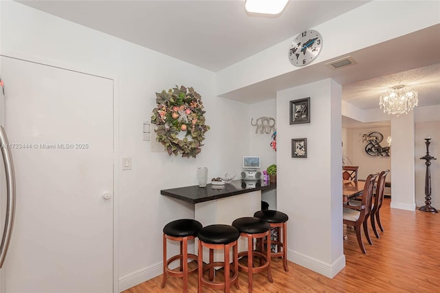 kitchen featuring a kitchen breakfast bar, light wood-type flooring, and a chandelier