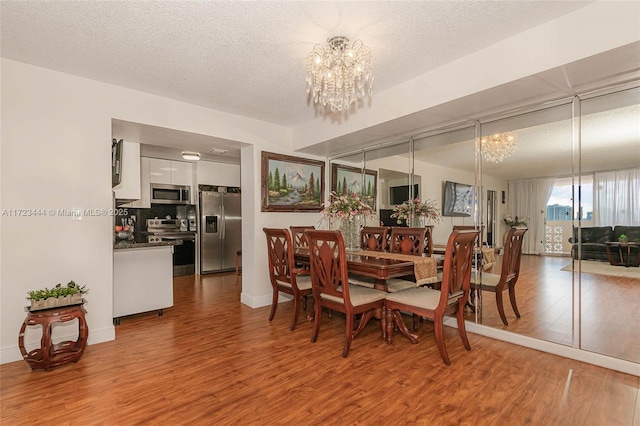 dining area with hardwood / wood-style floors, a textured ceiling, and a notable chandelier