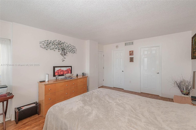 bedroom with light hardwood / wood-style floors and a textured ceiling