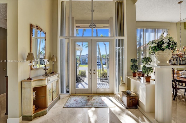 interior space featuring a textured ceiling, a high ceiling, and french doors