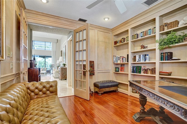 sitting room featuring french doors, a textured ceiling, light hardwood / wood-style floors, and ceiling fan