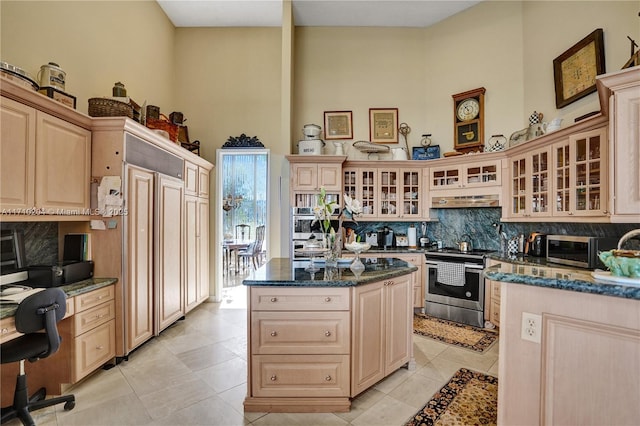 kitchen with stainless steel appliances, dark stone countertops, decorative backsplash, light brown cabinetry, and light tile patterned flooring