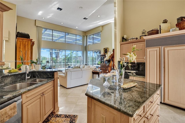 kitchen featuring dark stone counters, a kitchen island with sink, sink, paneled built in fridge, and dishwasher