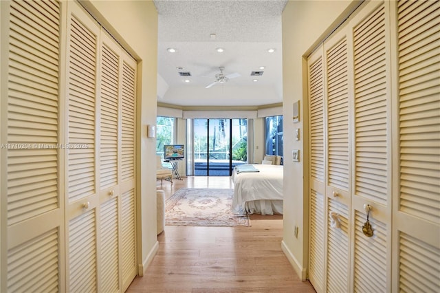 corridor with light hardwood / wood-style floors and a textured ceiling