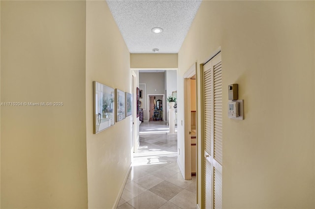 hall featuring light tile patterned flooring and a textured ceiling