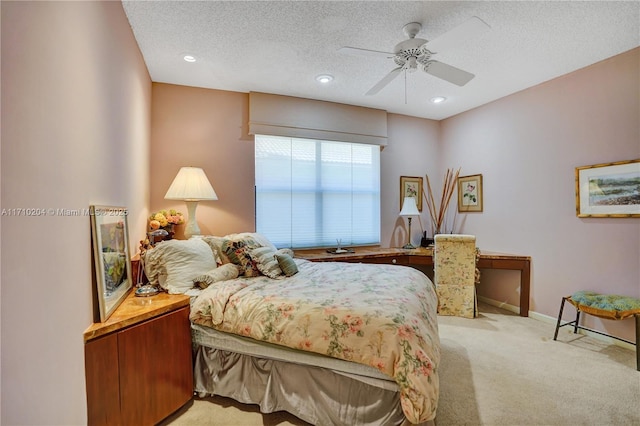 bedroom with ceiling fan, light carpet, and a textured ceiling