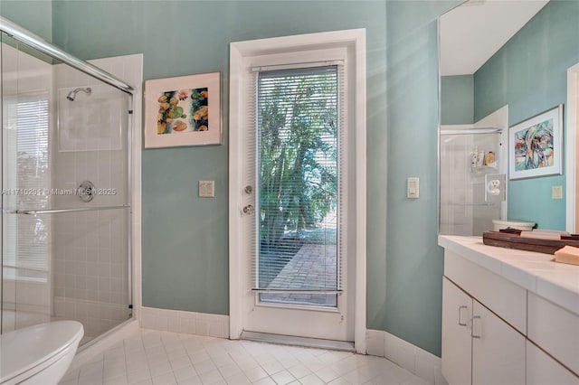 bathroom featuring toilet, vanity, tile patterned floors, and a shower with shower door