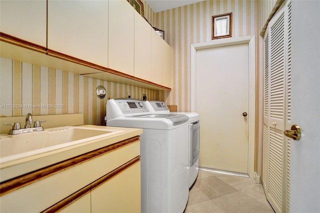 laundry room featuring washing machine and clothes dryer, sink, light tile patterned flooring, and cabinets