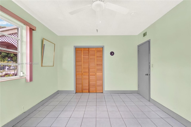 spare room featuring a wealth of natural light, ceiling fan, and light tile patterned floors