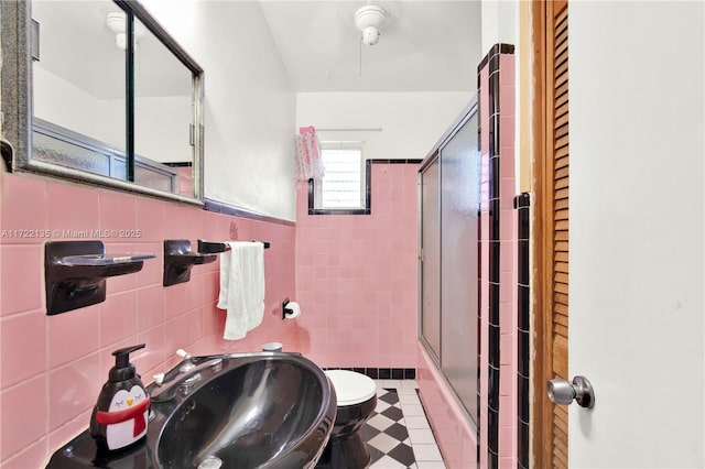 bathroom with tasteful backsplash, sink, tile walls, toilet, and a shower with shower door