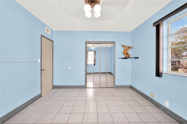 tiled spare room with ceiling fan and a textured ceiling