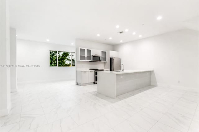 kitchen with a kitchen breakfast bar, white cabinetry, appliances with stainless steel finishes, and kitchen peninsula