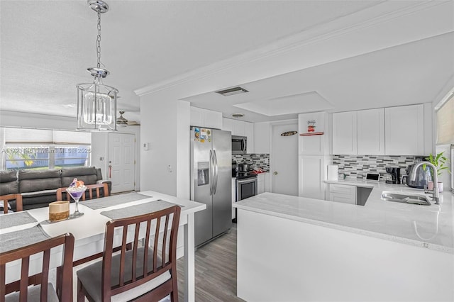 kitchen featuring kitchen peninsula, stainless steel appliances, sink, a notable chandelier, and white cabinets