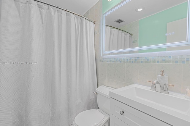 bathroom with vanity, toilet, and tile walls