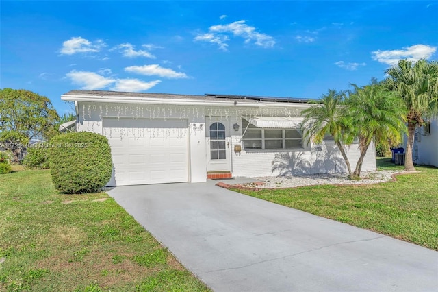 ranch-style house with solar panels, a garage, and a front yard