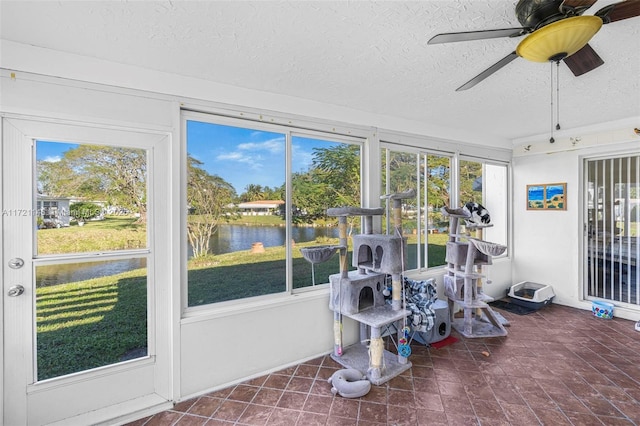 sunroom featuring a water view and ceiling fan