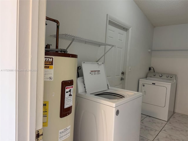 washroom featuring separate washer and dryer, water heater, and a textured ceiling