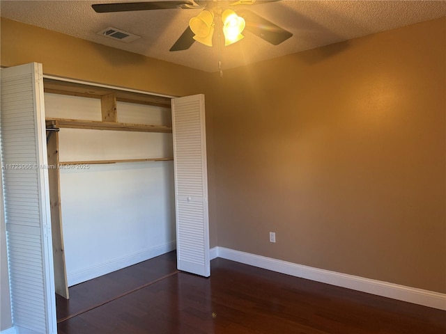 unfurnished bedroom with a textured ceiling, a closet, ceiling fan, and dark wood-type flooring