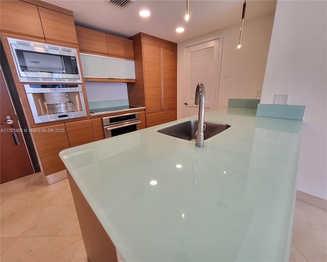 kitchen with appliances with stainless steel finishes, sink, and light tile patterned floors